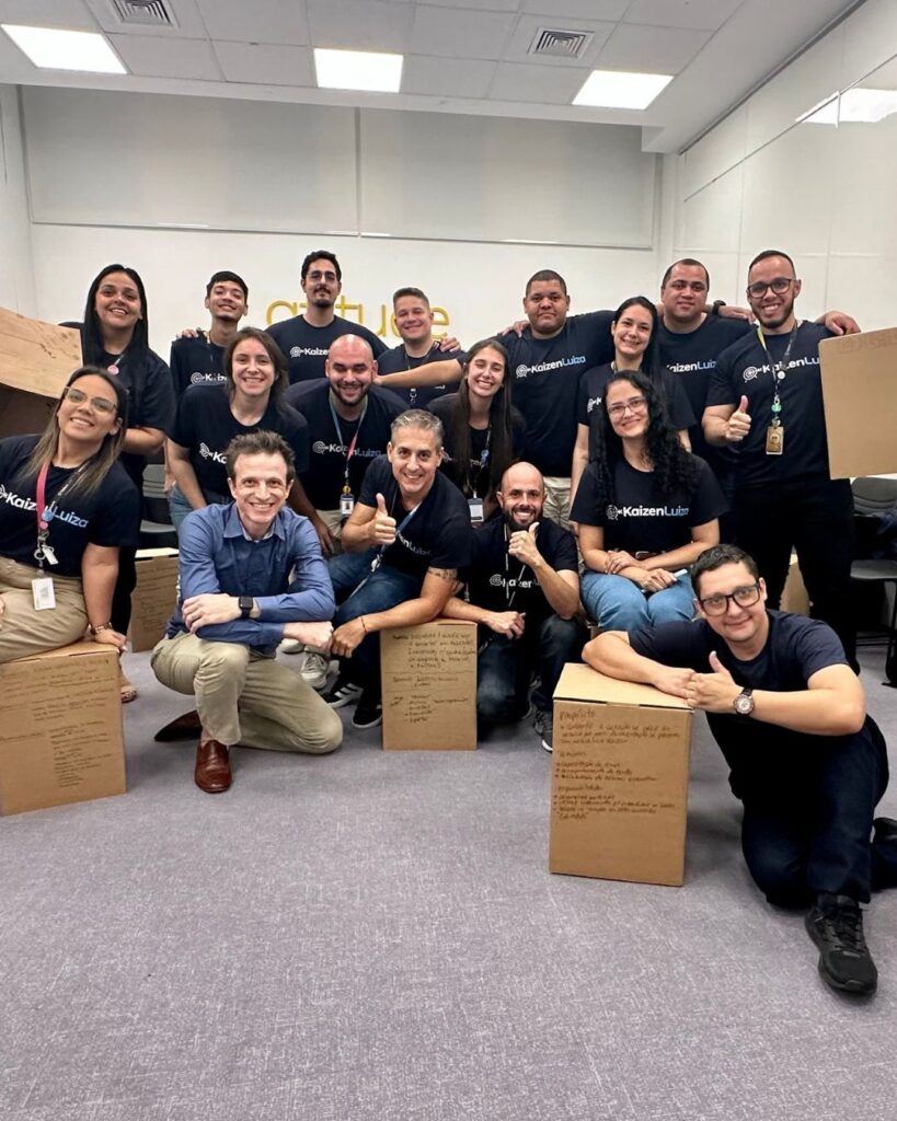 Grupo de colaboradores reunidos após uma atividade colaborativa, com caixas contendo anotações visíveis, conteúdo que faz parte do Team Building Accountability Club da Aldeia Incompany. Essa prática reforça o compromisso da Magalu com o desenvolvimento de profissionais por meio de experiências coletivas.