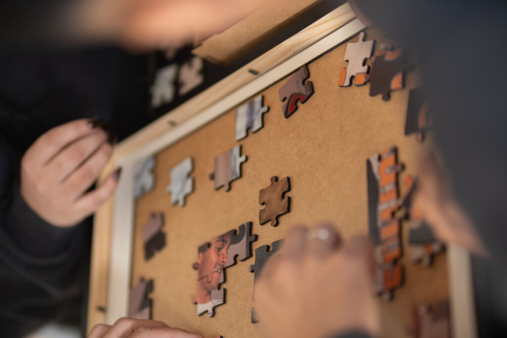 Mãos de colaboradores montando peças de quebra-cabeça durante o Team Building realizado e mostrando na prática a colaboração no ambiente de trabalho
