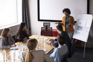 Workshop Primeira Liderança com profissional apresentando estratégias para novos líderes, enquanto equipe assiste atenta à apresentação.